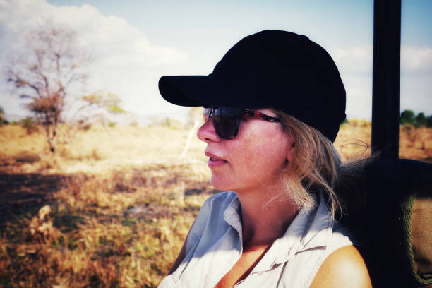 Caucasian woman  wearing a cap and sunglasses on a jeep safari in the Mikumi National Park in Tanzania.