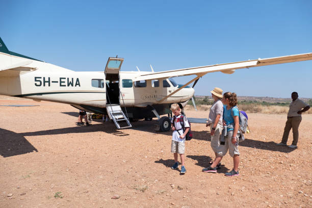 Mikumi National Park, Tanzania - August 05, 2018: A family with children is waiting near a  Cessna 208 B Grand Caravan after arrival at the airstrip of the Ruaha National Park. The safari charter is from Safari Airlink. This airline  is offering flights to remote areas in Southern Tanzania.