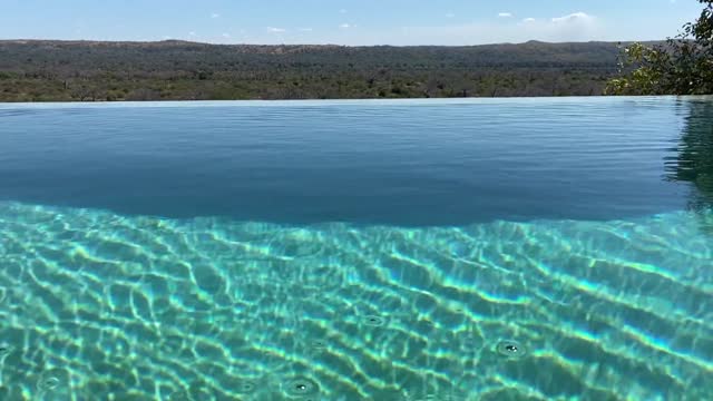 Ripples moving and reflecting in the water in a turquoise infinity pool on a sunny day at a safari lodge overlooking the Ruaha National Park in Tanzania, Africa