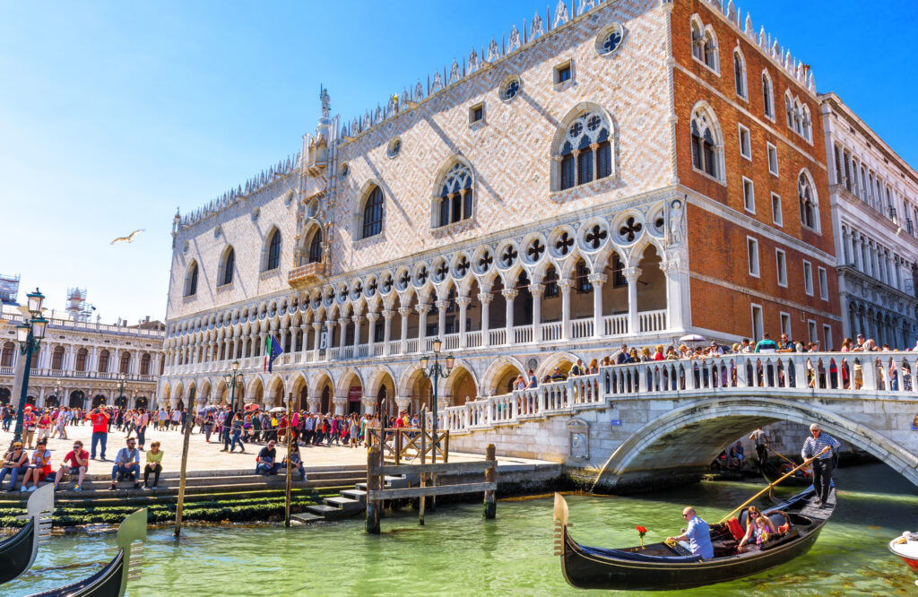 Venice, Italy - May 21, 2017: Doge's Palace by San Marco in Venice. It is one of the top tourist attractions of Venice. Beautiful view of the Venice embankment with people and gondola in summer.