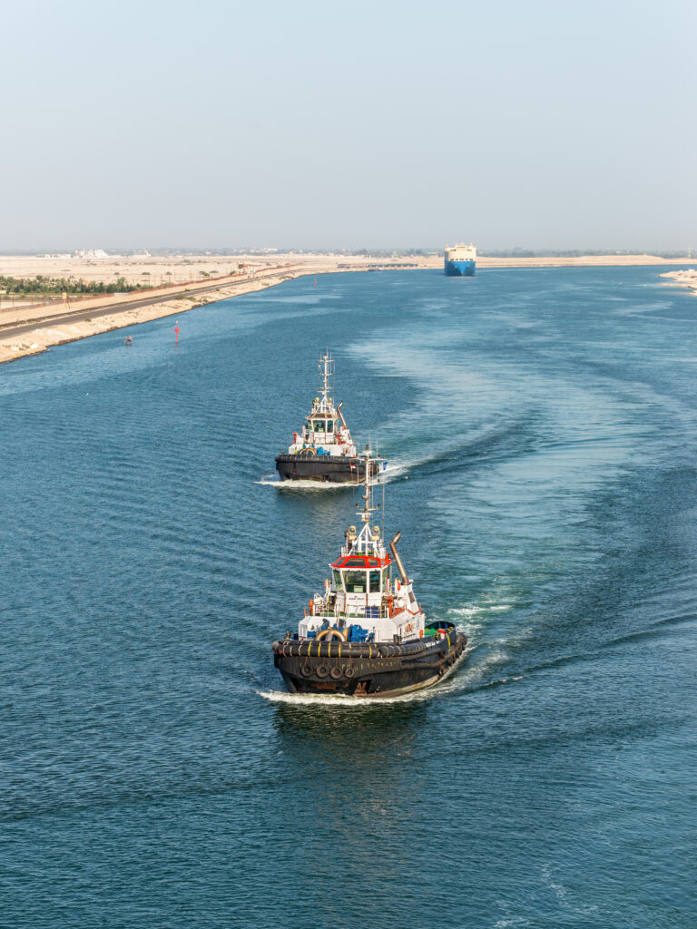 El Qantara, Egypt - November 14, 2019: Tugboats accompanies the ships. Ships passing through the Suez Canal in Egypt, Africa.