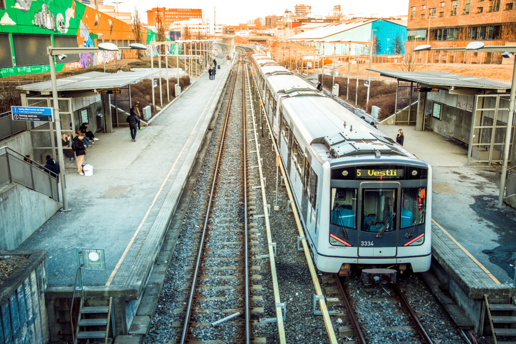 People are waiting for the metro train nr 5 towards Vestli at the outdoor Hasle station in Oslo in the in the late afternoon sun, Oslo, Norway - March 11, 2022