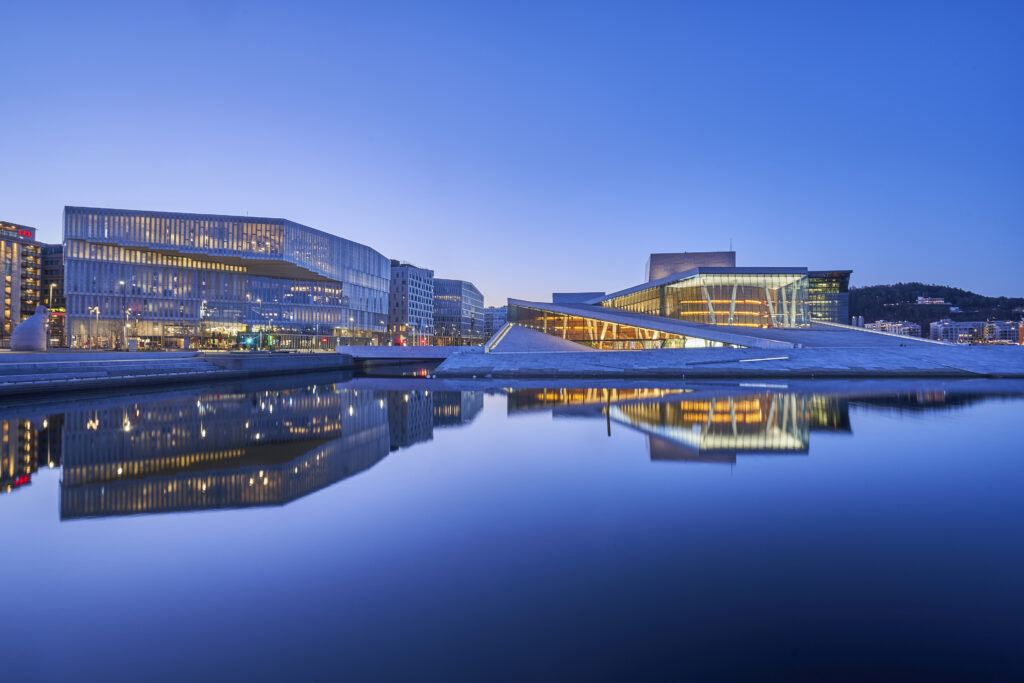 Oslo, Norway – April 14, 2022: Oslo's Bjorvika (Inner Harbor) during sunrise with the calm water reflecting the famous Oslo Opera House.