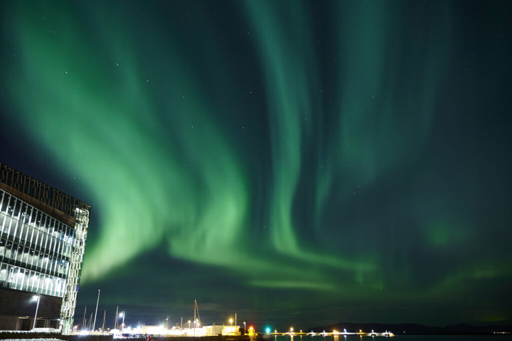 The Harpa Concert Hall illuminated with northern lights at night in Reykjavik, Iceland.