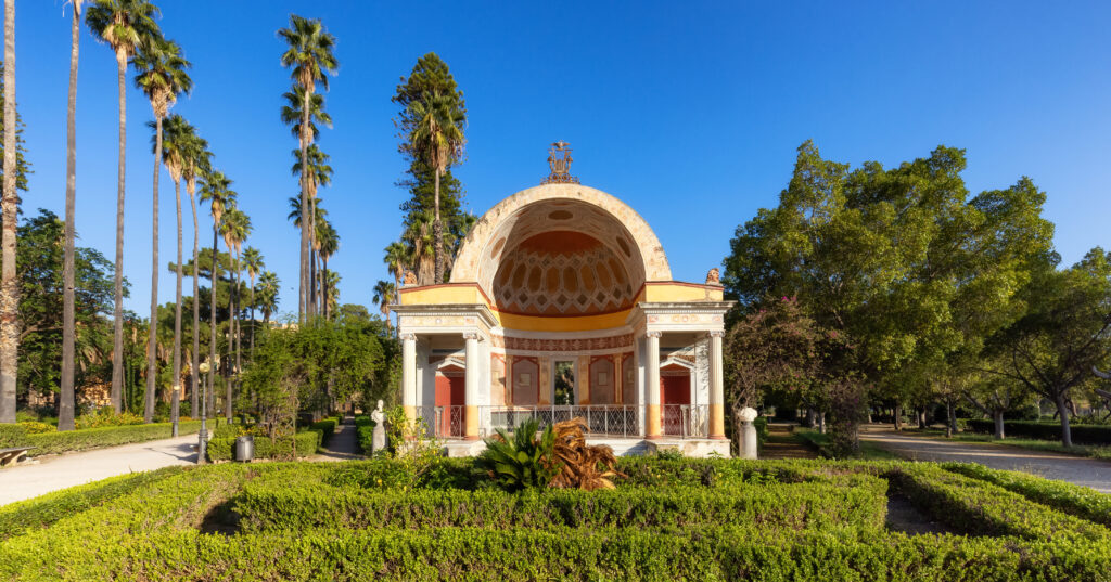 Path with vibrant green trees in city park, Villa Giulia. Palermo, Sicily, Italy.