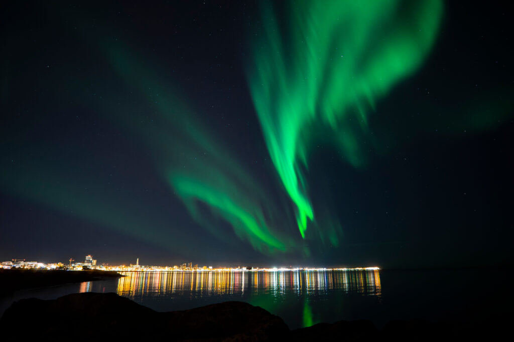 A low angle shot of the bright green northern lights over Reykjavik, Iceland