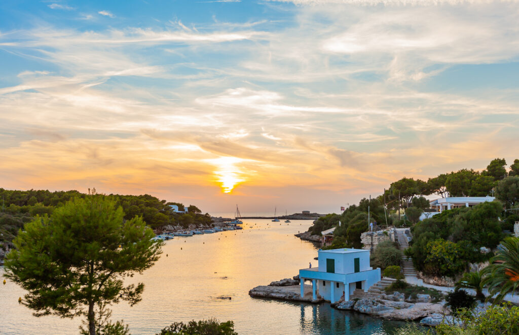 This stunning aerial photograph captures the breathtaking beauty of Menorca's Macarella and Macarelleta bays. With the sun shining brightly and crystal-clear waters reflecting the sky, the scene exudes serenity and tranquility. The white sand beaches, surrounded by rocky cliffs and lush vegetation, provide a natural oasis for sunbathers and swimmers alike. Whether you're an avid beach-goer or simply appreciate the stunning beauty of nature, this view of Macarella and Macarelleta bays is sure to take your breath away.