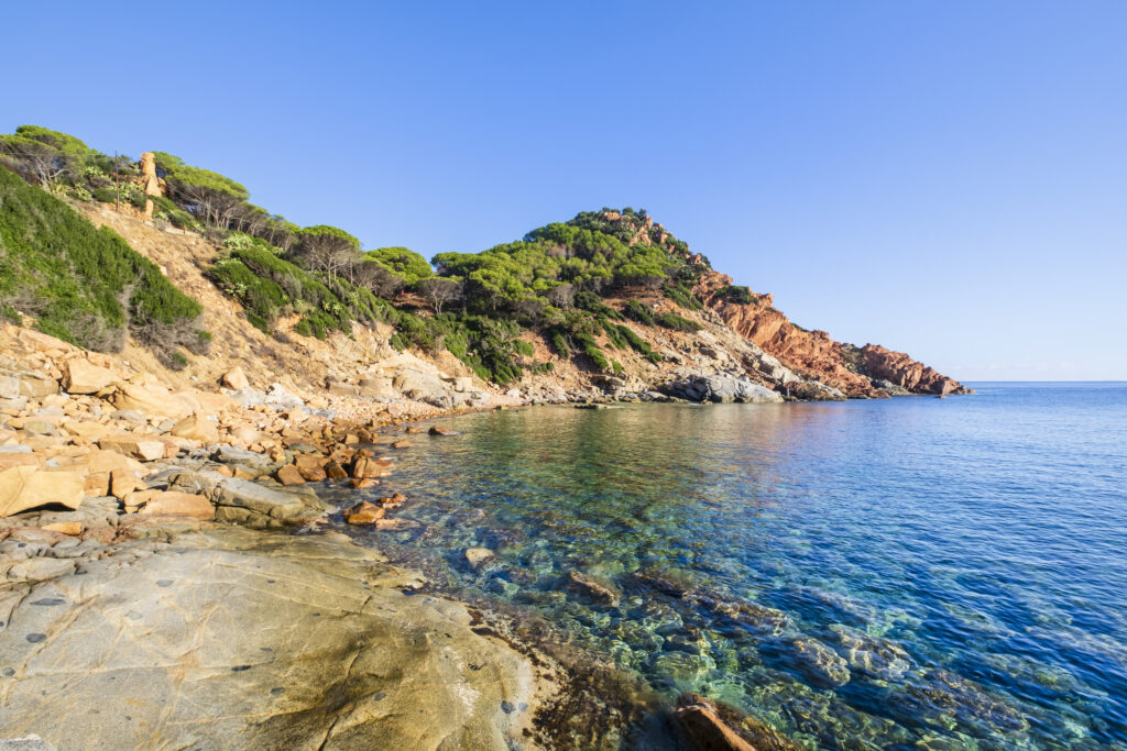 Cala Moresca of Arbatax, a bay protected by red porphyry cliffs covered by Mediterranean scrub with a beach mostly made up of granite pebbles