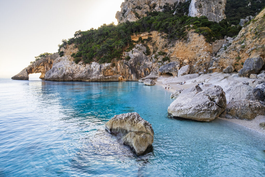 Crystal water laps the Cala Goloritzé, a cove of white small pebbles protected by a rugged cliff with a natural arch