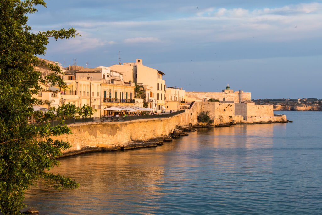 Panorama Syracuse, Ortiggia, Sicily, Italy, houses facing the sea in the morning, in the background of blue sky and reflections on the sea