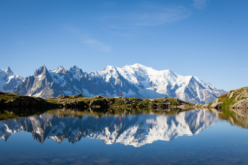 Runner in red runs in the French Alps near Chamonix with the Mont Blanc in the background.