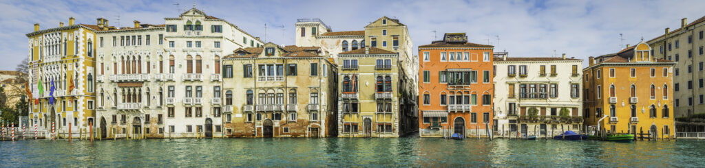 Colourful villas and palazzo reflecting in the tranquil waters of the Grand Canal in the Academia district of Venice, Italy.