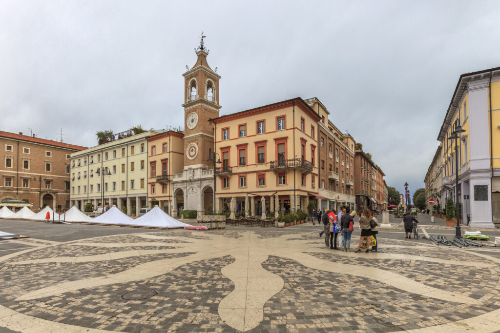 Rimini, Italy - October 23, 2014: People strolling in Piazza Tre Martiri in a cloudy day of end October. The large city square, of ancient origin, is now dedicated to the martyrs and to the fallen of World War II.